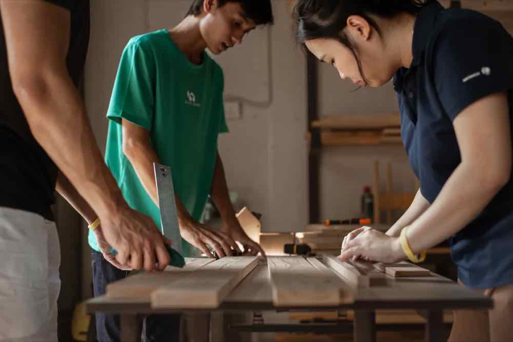 Two trainees fitting cabinet parts at a bench