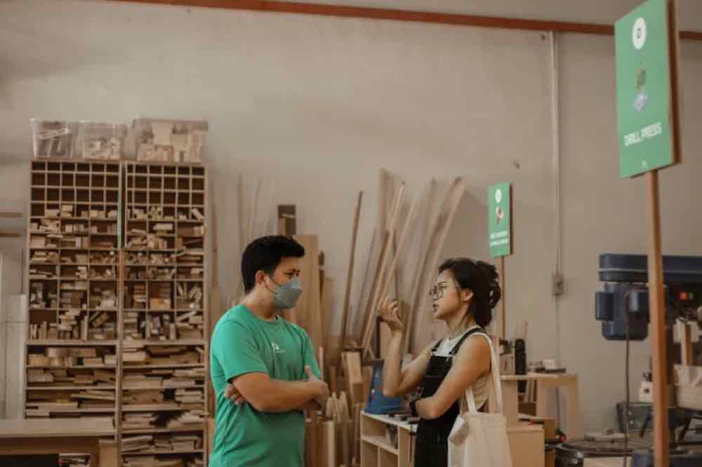 Jon talking with a visitor beside the timber rack at KitaBina