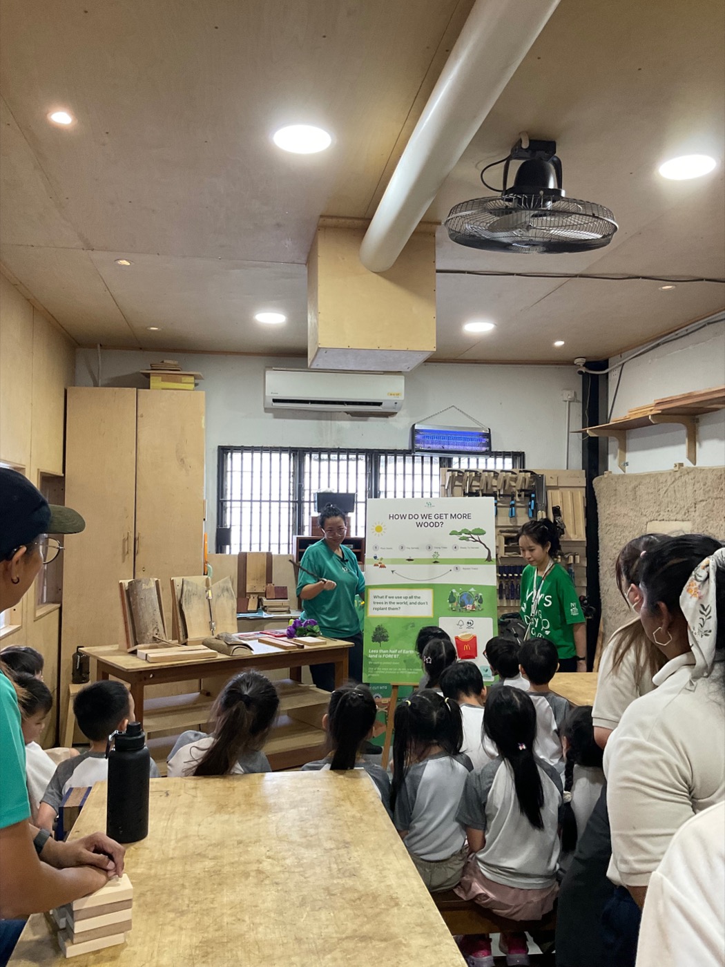 An instructor teaching a class of young children about wood at KitaBina
