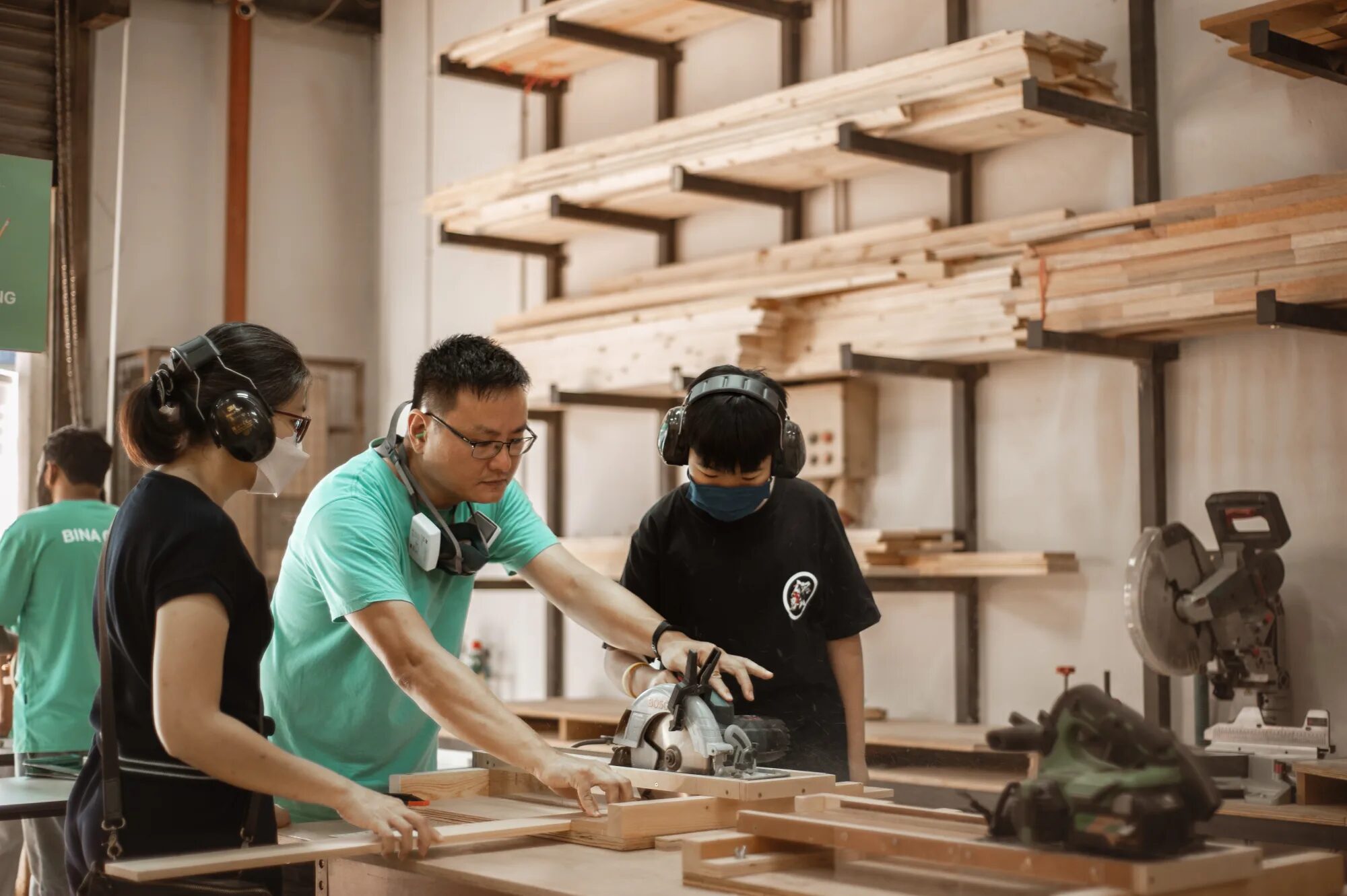 An instructor guiding two makers through a cut at a Pesta Bina work table