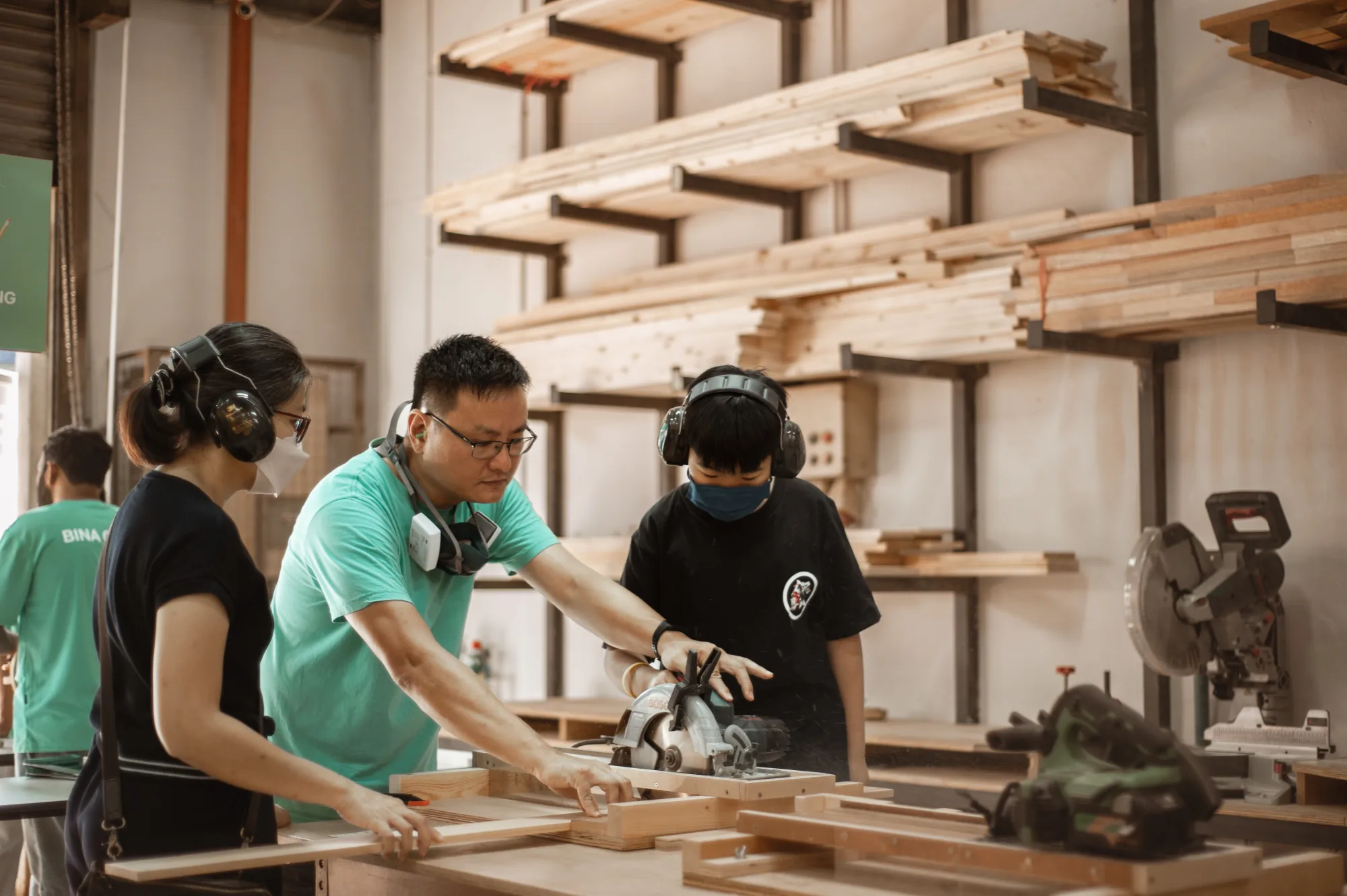 An instructor guiding two makers through a cut at a Pesta Bina workbench