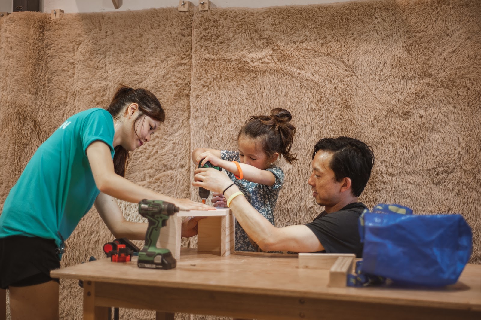 An instructor guiding a maker's hands at the bench